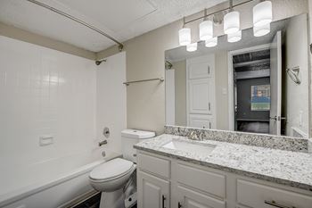 Updated bathrooms with custom lighting, granite countertops and a curved shower bar